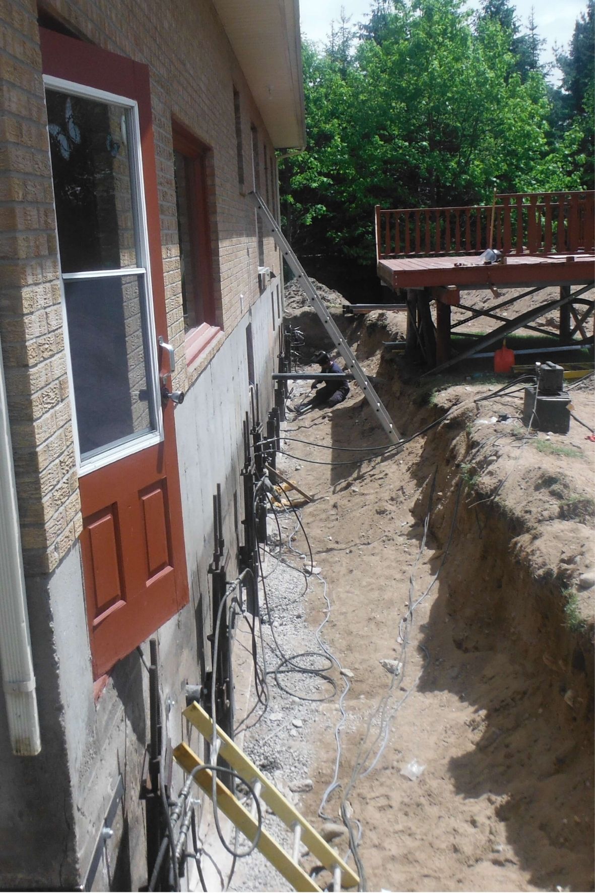 Excavation le long d’un mur de fondation avec éléments métalliques installés et accès dégagé autour du bâtiment  à Ahuntsic – Cartierville