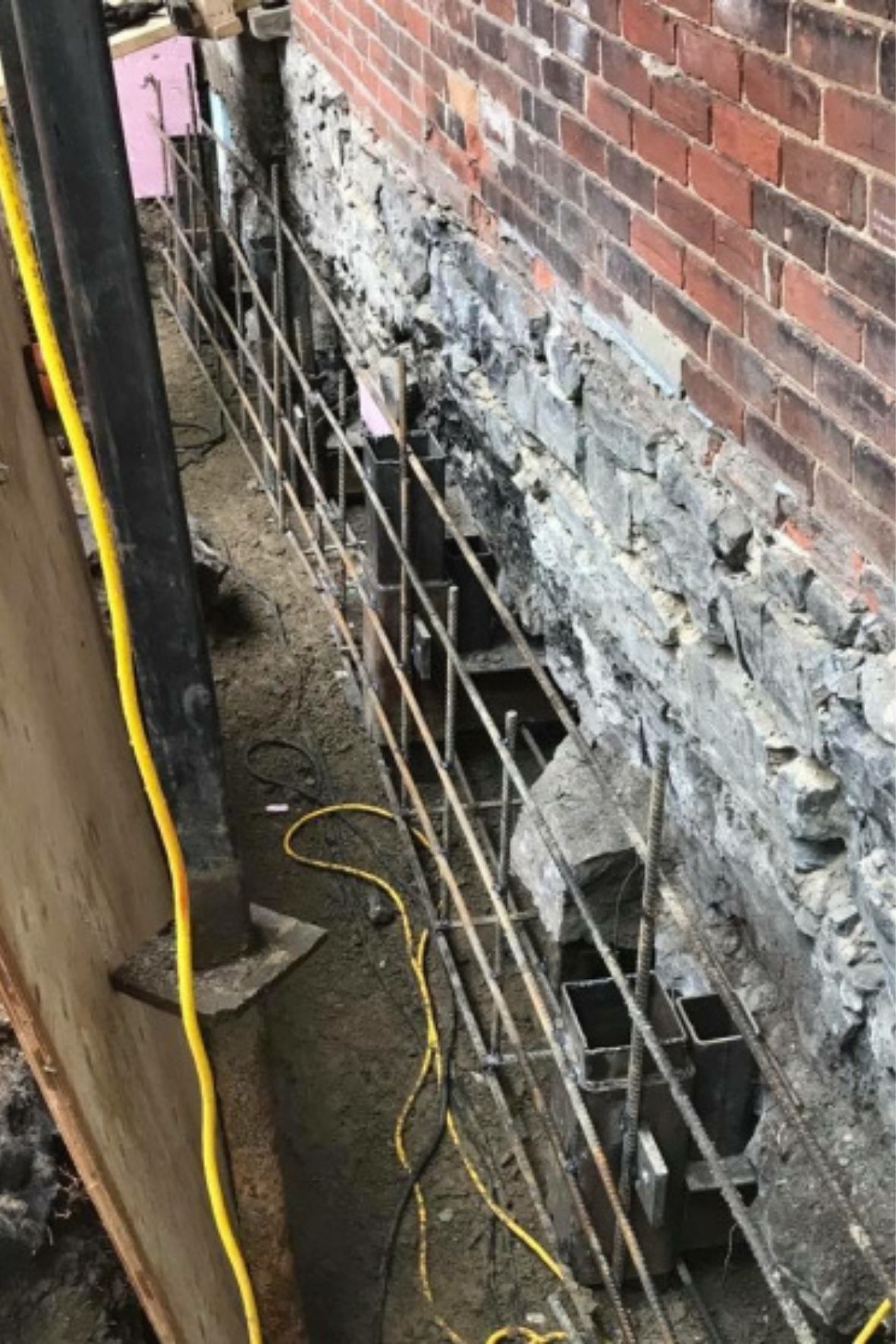 Mur de fondation exposé avec éléments de renfort métalliques visibles dans une zone excavée  à Lachine