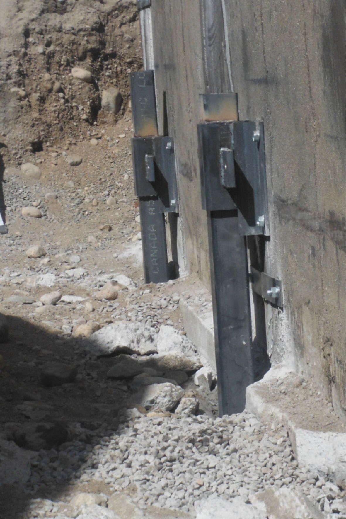 Détails rapprochés de supports métalliques installés au bas d’un mur de fondation sur sol excavé  à Mercier